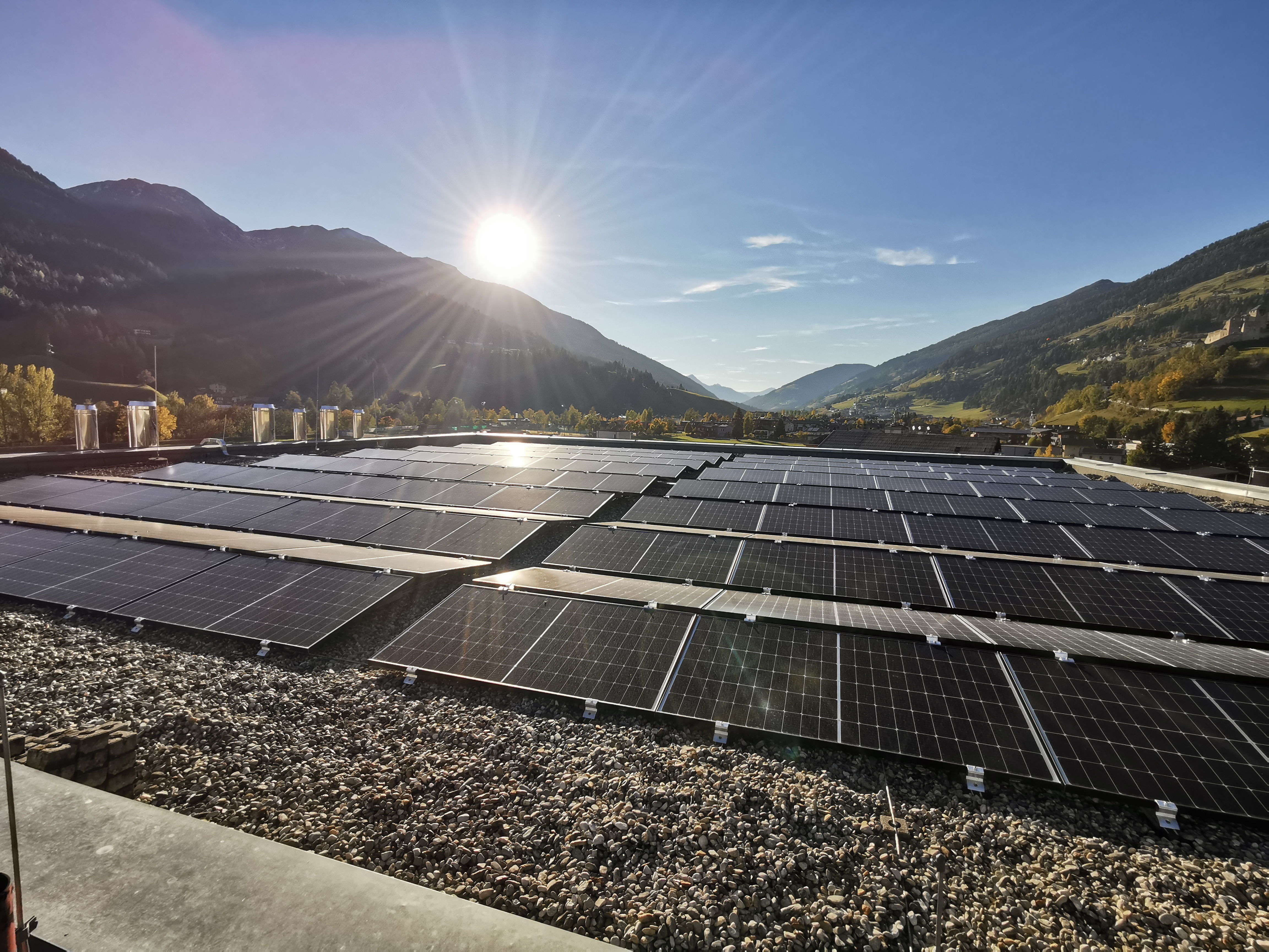 Photovoltaik-Flachdachanlage mit Bergpanorama und Sonne